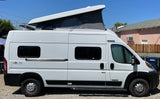 Side view of a white Winnebago Solis camper van with a raised pop-top roof, perfect for your next rv rental.