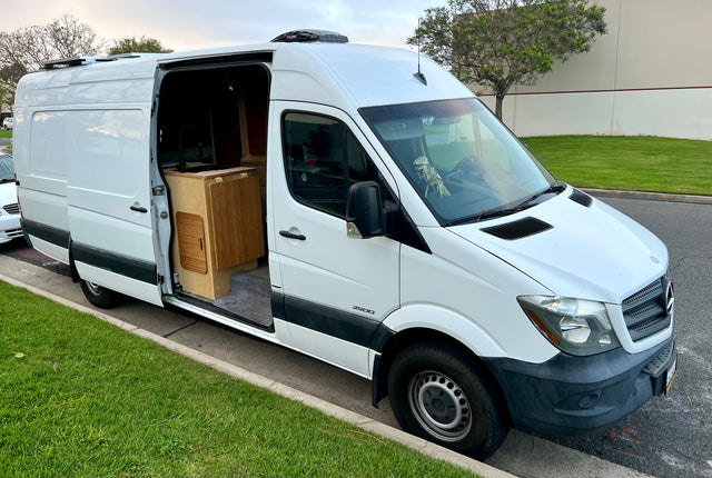 White Mercedes Sprinter camper van for rv rental, showing interior kitchen and roof solar panels.
