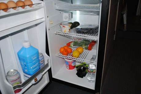 Inside an RV rental's stocked mini-fridge: eggs, fresh fruit, veggies, and drinks for your adventure. Stay refreshed!