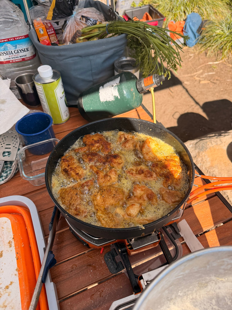 Outdoor cooking on an RV rental trip: Frying golden chicken in a pan on a portable propane stove. — photo 18