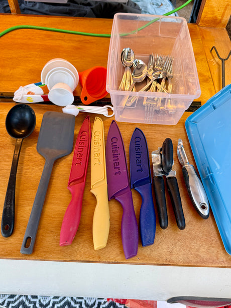 RV rental kitchen essentials: measuring cups, spatulas, colorful Cuisinart knives, silverware, can opener, and peeler.
