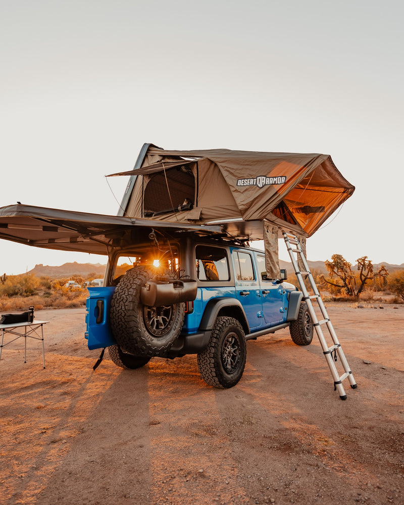 Overland-ready blue Jeep with a deployed rooftop tent in a desert sunset. The ultimate RV rental for your outdoor camping adventures. — photo 6