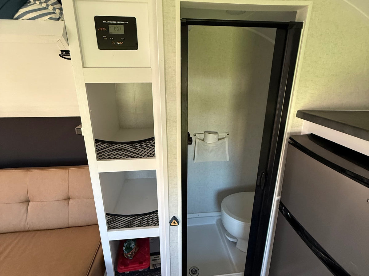  parked on a street. Texas plate visible.|Step inside this modern rv rental! It features a cozy bed — photo 5