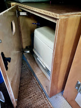 RV rental: Custom-built cabinet with an open door revealing a Porta Potti 100 Series portable toilet inside.