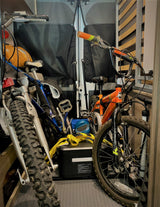 Three bicycles, a power station, and a helmet are packed in an RV rental's rear cargo area, ready for adventure.