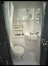 RV rental's compact wet bath: all-in-one toilet, sink, and shower. White molded interior, ideal for camping.