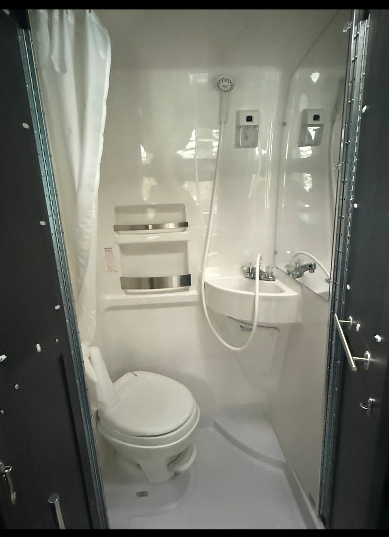 RV rental's compact wet bath: all-in-one toilet, sink, and shower. White molded interior, ideal for camping. — photo 9
