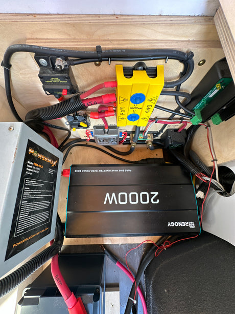 Inside an RV rental: view of the electrical system with a Powermax converter, Renogy 2000W inverter, and safety wiring.
