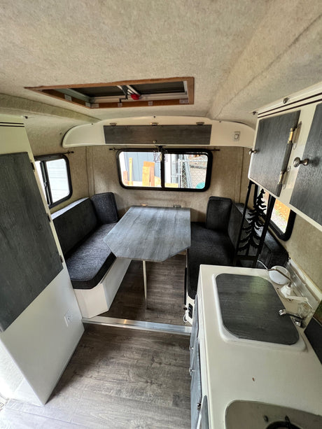 Inside this RV rental: a modern kitchen, comfy dining booth, and bright interior, ready for your road trip comfort.