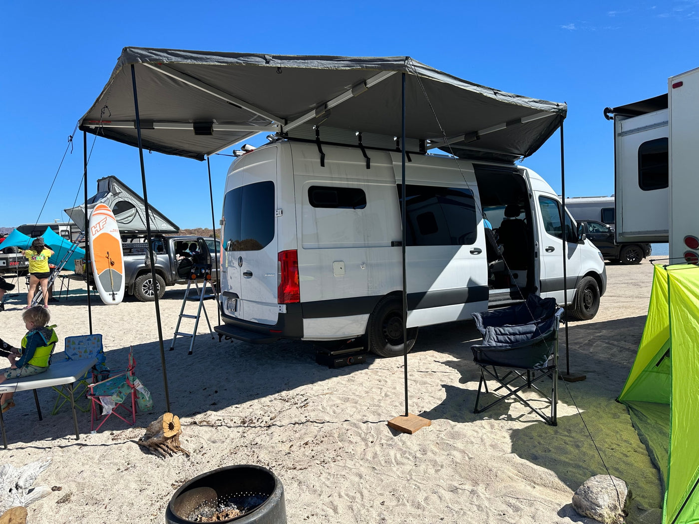 White camper van with an extended awning, set up at a sandy rv rental campsite. Perfect for sunny outdoor adventures. — photo 5