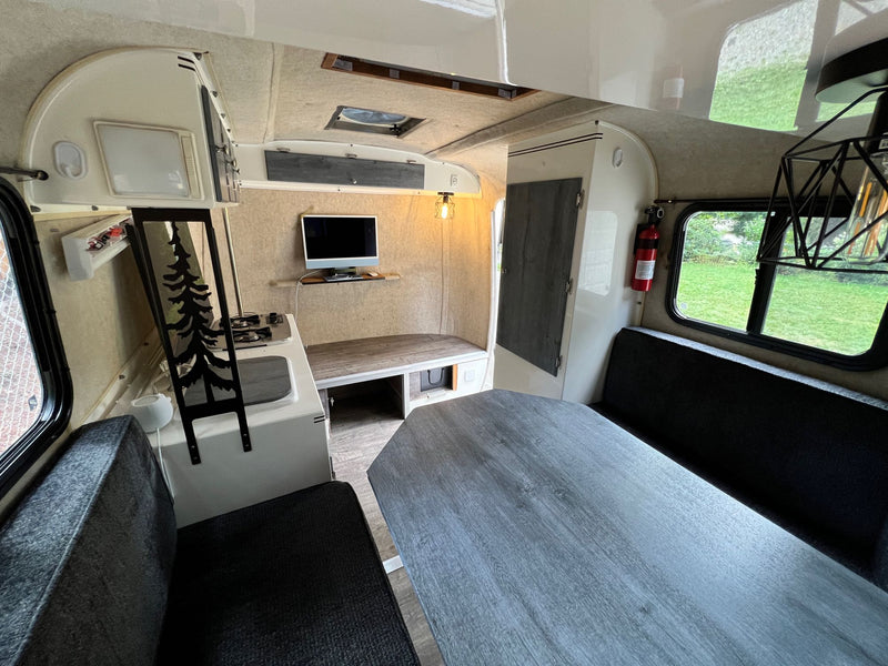 Inside a compact RV rental: modern interior with grey dinette, kitchen, TV, and comfy seating. — photo 7