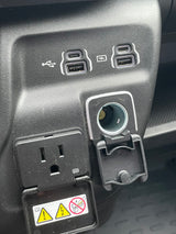 RV rental: Vehicle charging station with USB-A, USB-C, 12V, and a covered 110V AC outlet for electronic devices.