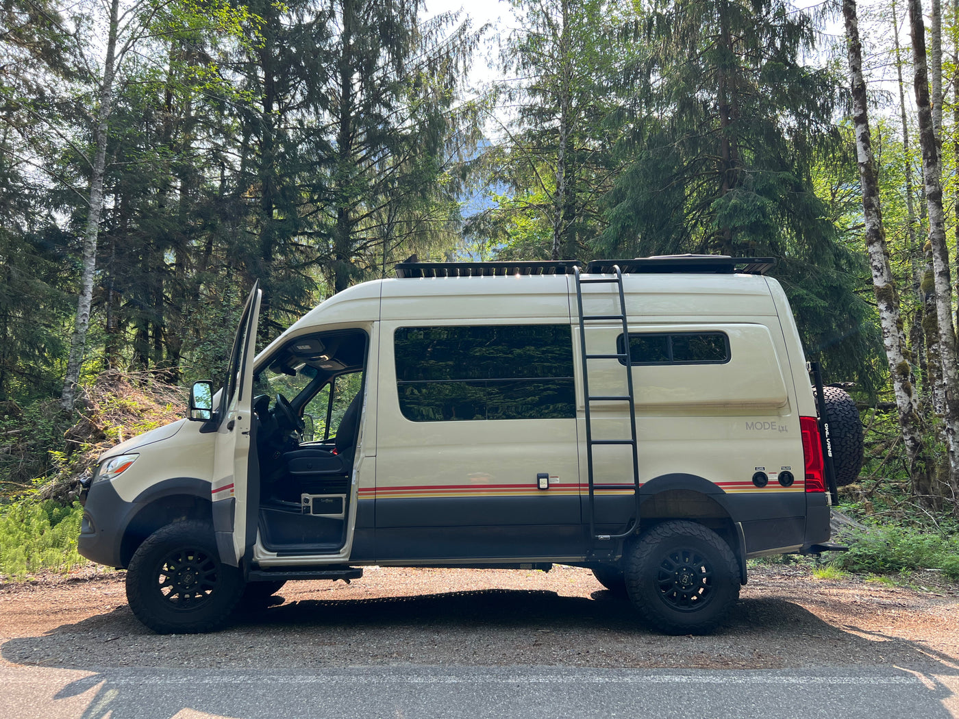 Cream 'MODE 4x4' off-road camper van, an adventure rv rental, parked in a lush forest. Driver door open. — photo 6