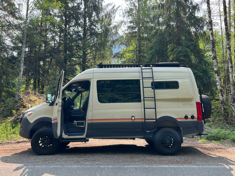 Cream 'MODE 4x4' off-road camper van, an adventure rv rental, parked in a lush forest. Driver door open. — photo 6