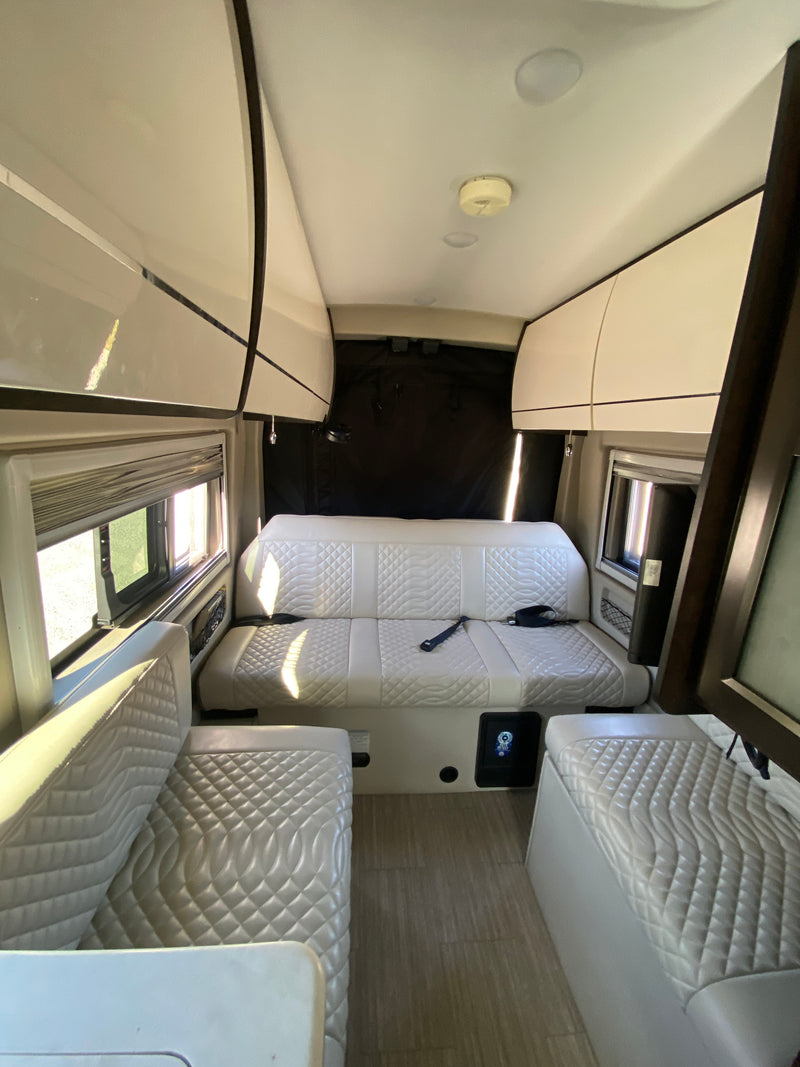 Spacious rv rental interior featuring light quilted seating, overhead storage, and large windows, perfect for travel. — photo 2