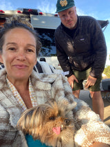 Relaxing RV rental journey! A couple and their shaggy dog cozy up with a blanket by their camper van.