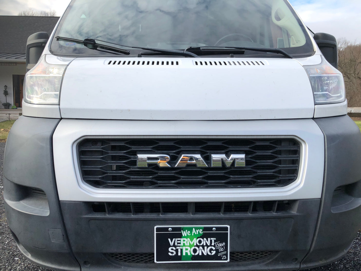 Front of a white Ram ProMaster van, popular for RV rental, showing its grille and "Vermont STRONG" plate.