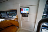Inside an RV rental: Digital power management screen (Victron), water pump/dump switches, cozy bed, and outdoor view.