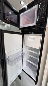  an excellent rv rental. Parked on asphalt next to modern houses.|Step inside this modern RV rental interior featuring a comfortable grey sofa