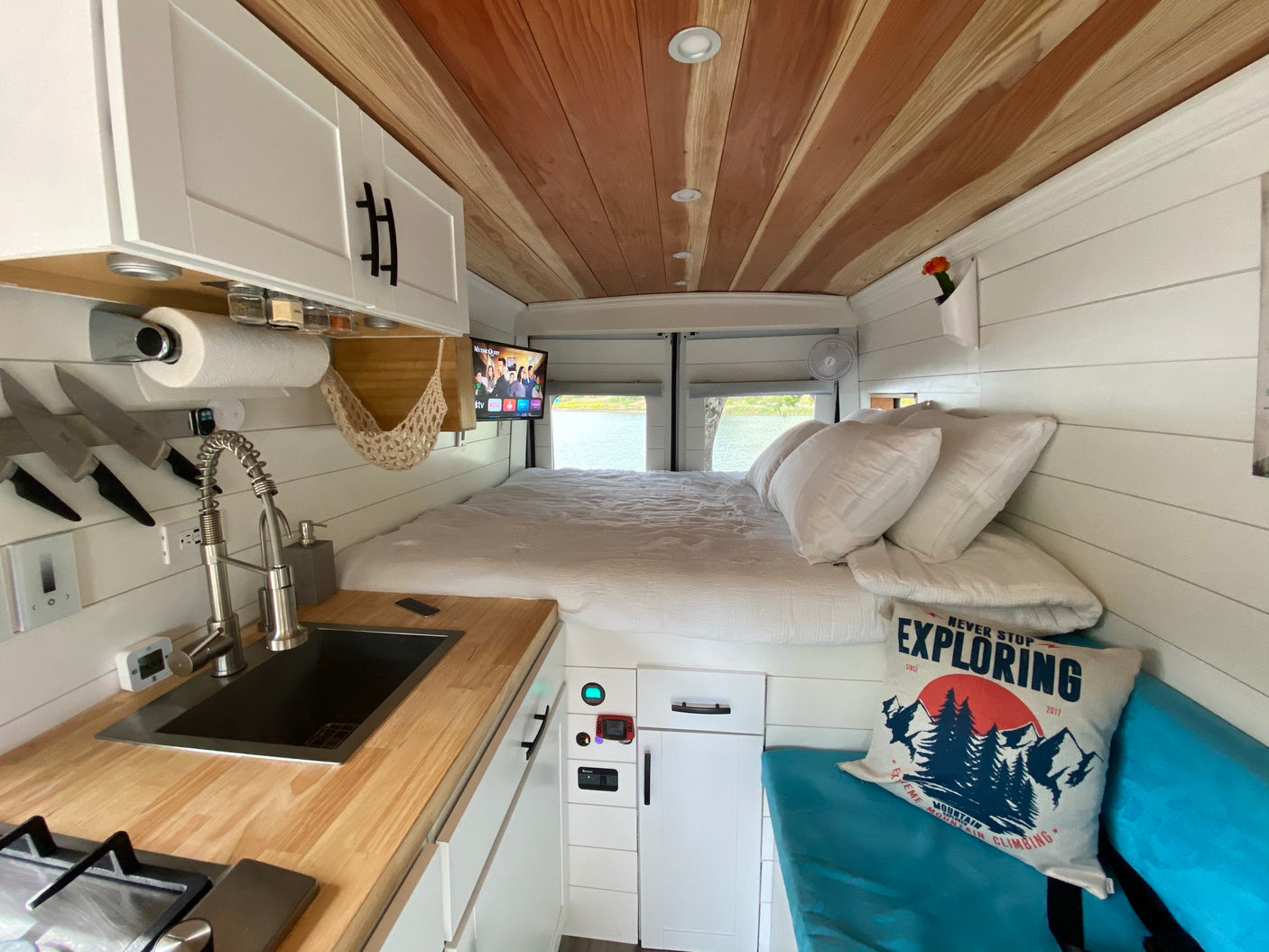 Explore in comfort with this rv rental! Features a compact kitchen, bed, and serene water views from this modern camper van interior.