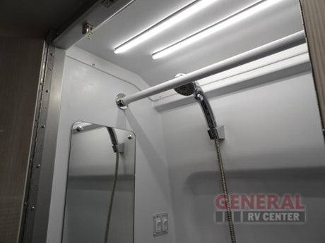 Bright RV rental shower stall with LED lights, a handheld showerhead, mirror, and grab bar.