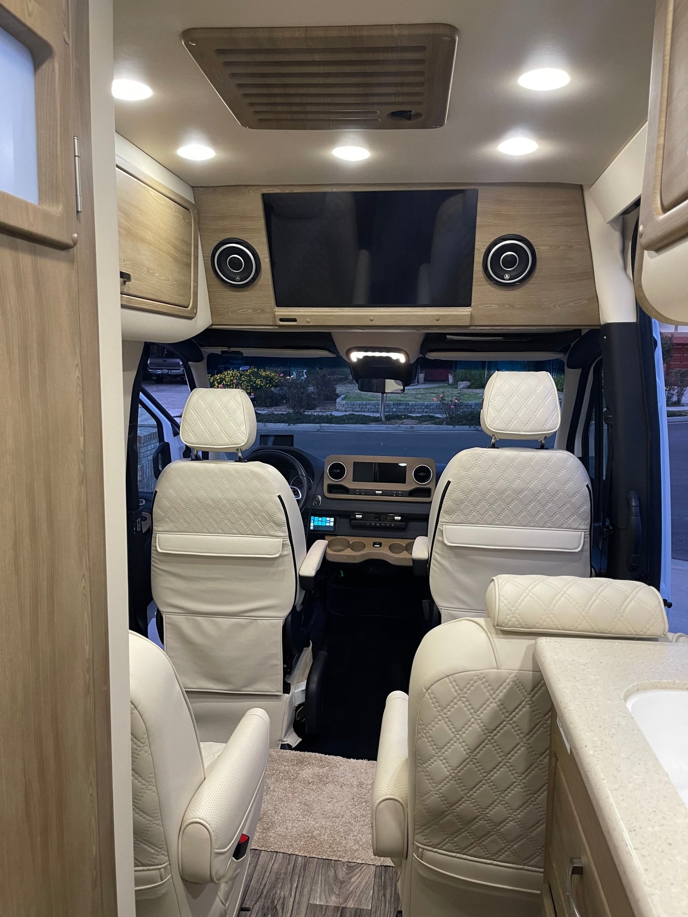 Premium RV rental interior with cream quilted seats, wood accents, TV, and a spacious front cabin view. — photo 7