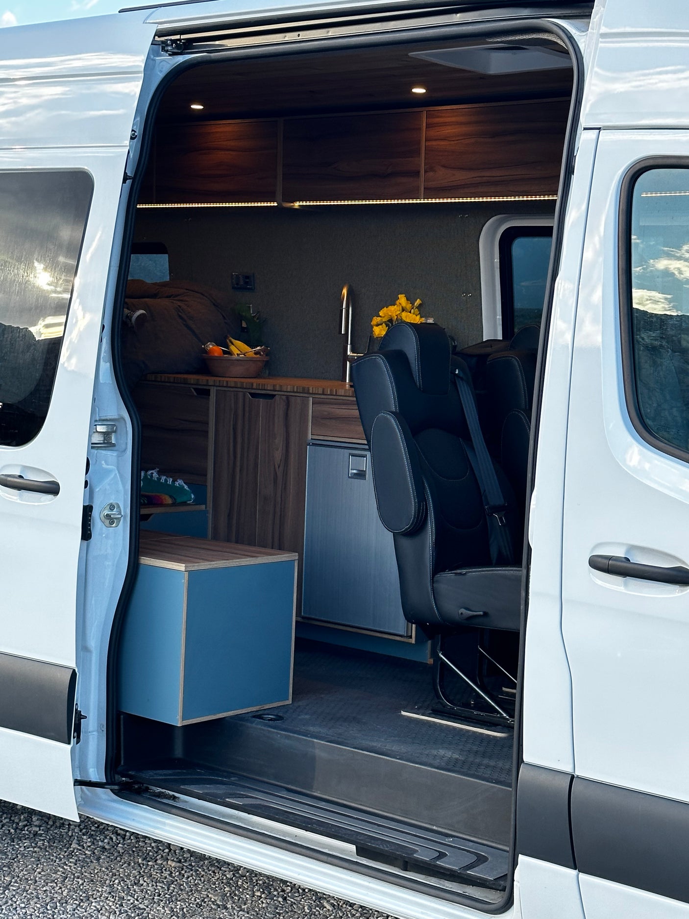 Explore this comfy RV rental camper van! Interior features a kitchen, bed, seating, and storage for your next adventure.