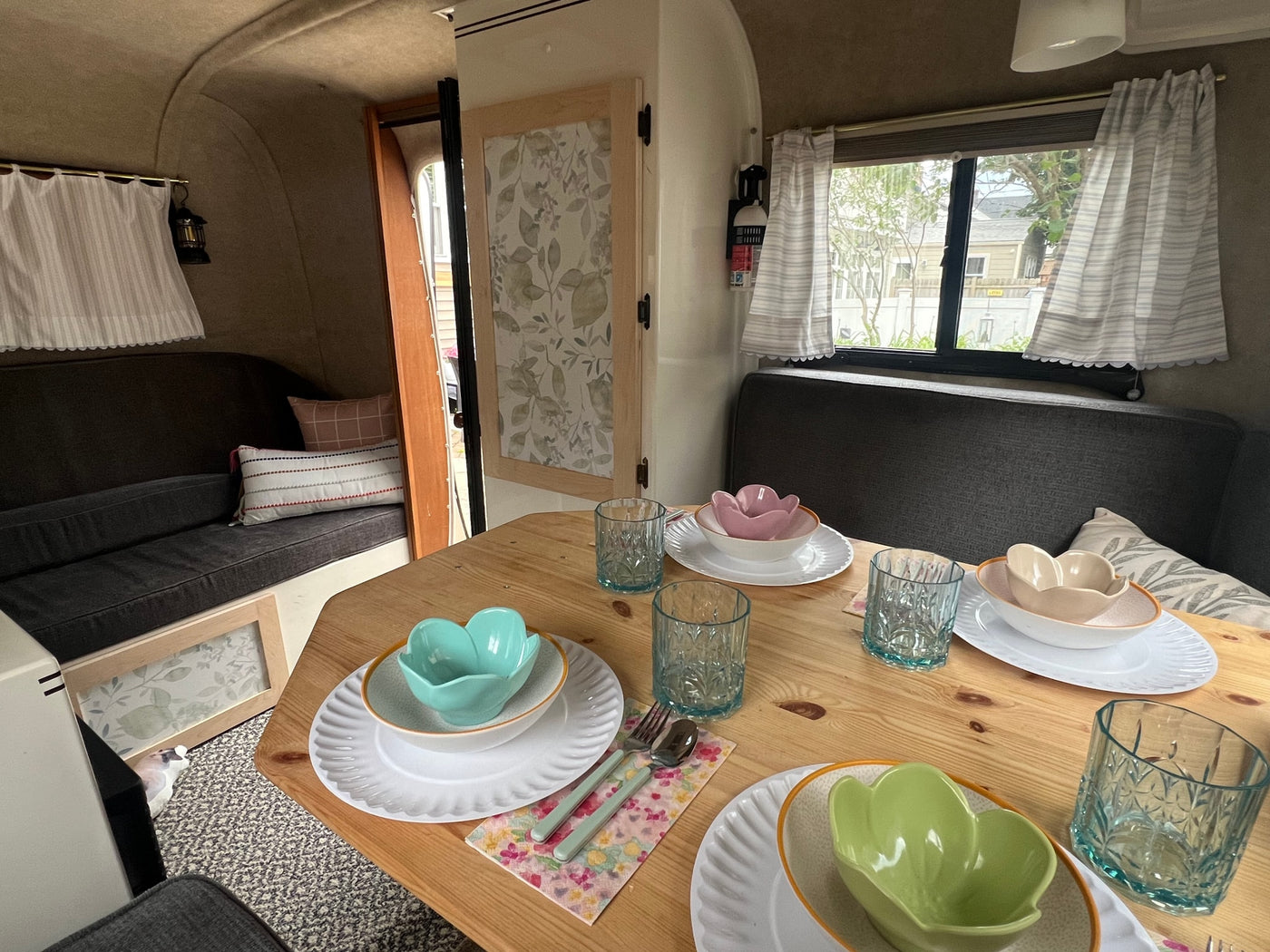 Stylish RV rental dining area set for four, featuring colorful flower bowls, patterned glasses, and cozy bench seating. — photo 7