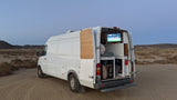 This rv rental camper van is parked in the desert, enjoying TV from inside. Ideal for van life adventure.