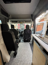 Inside a modern **rv rental** van. View from rear shows comfortable seating, neat flooring, and front cabin ready for travel.