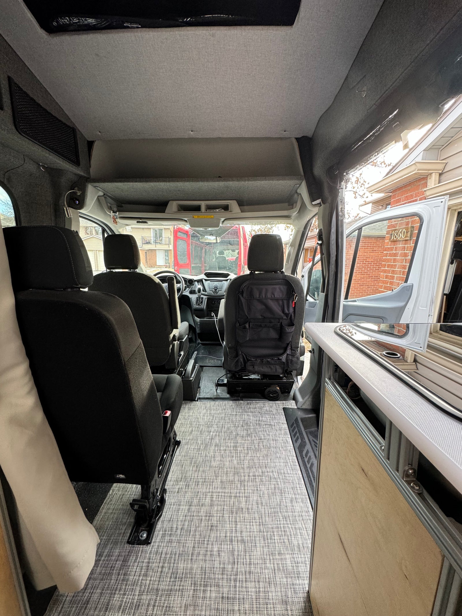 Inside a modern **rv rental** van. View from rear shows comfortable seating, neat flooring, and front cabin ready for travel.