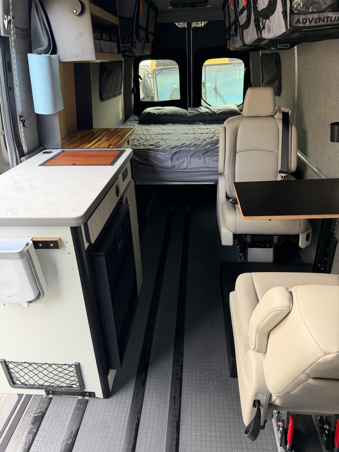 Spacious RV rental interior featuring a kitchenette, bed, comfortable seating, and smart storage, perfect for mobile living. — photo 5