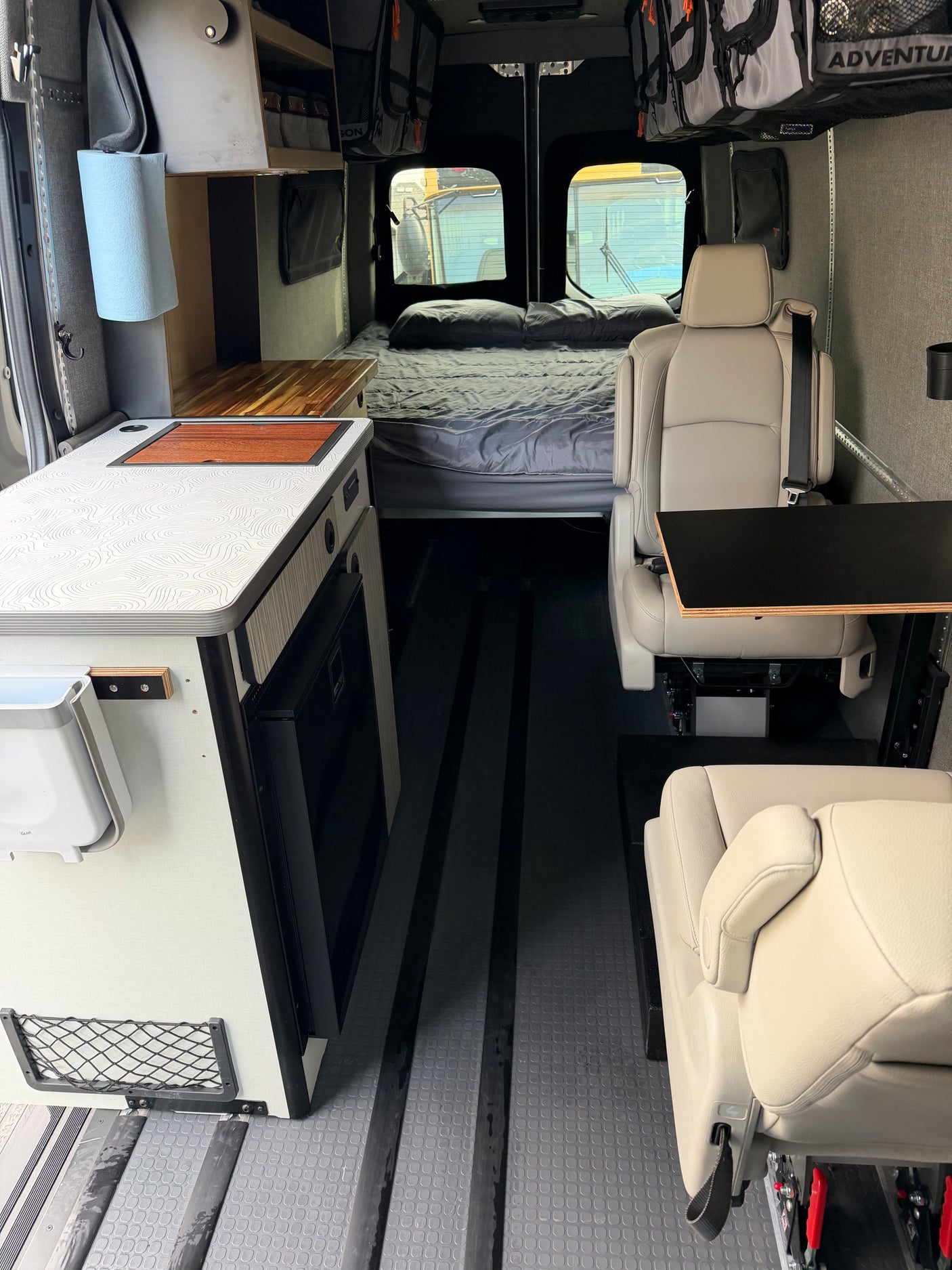 Spacious RV rental interior featuring a kitchenette, bed, comfortable seating, and smart storage, perfect for mobile living.