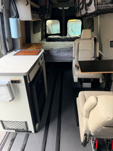 Spacious RV rental interior featuring a kitchenette, bed, comfortable seating, and smart storage, perfect for mobile living.