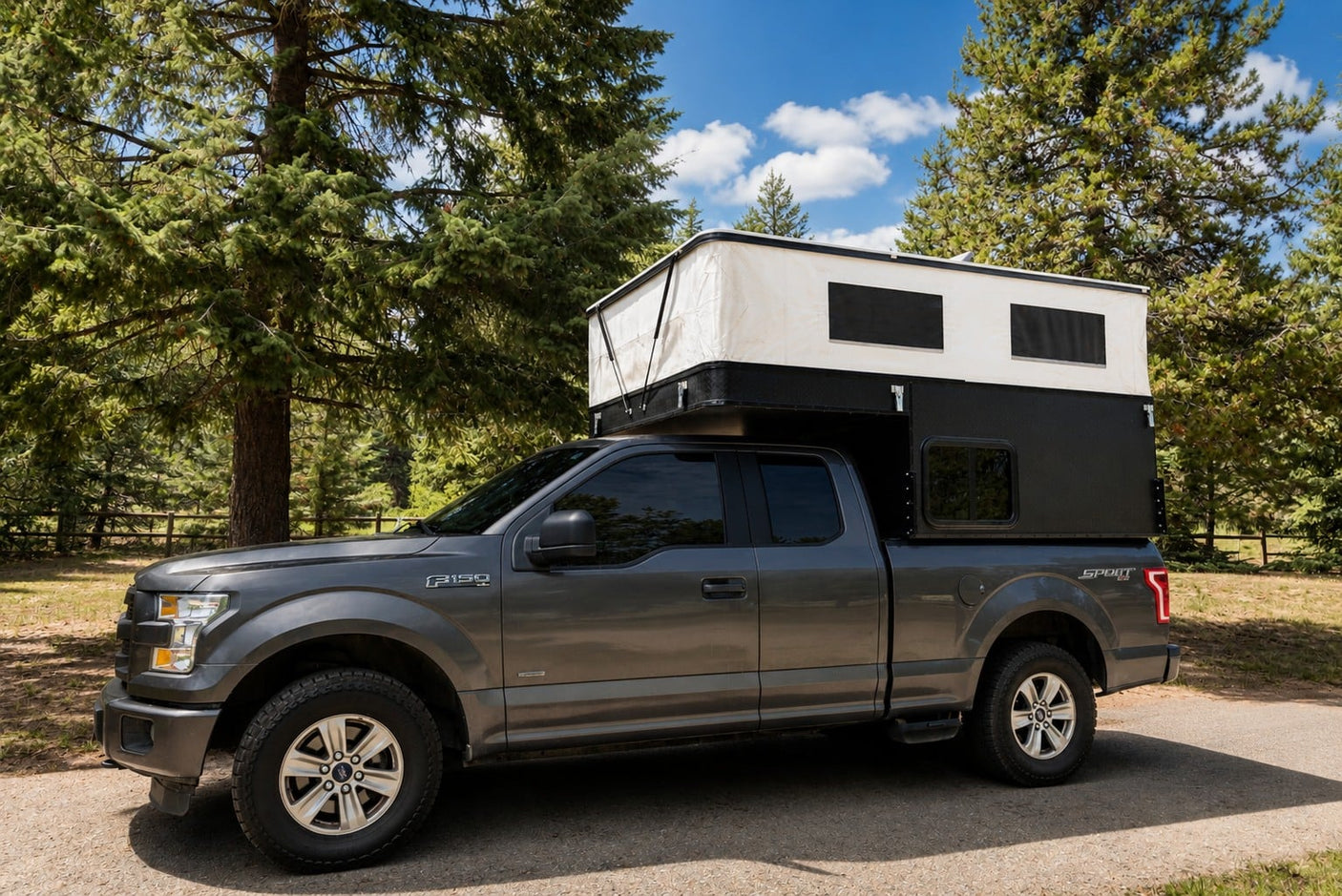 Grey Ford F-150 pickup with pop-up camper, ideal RV rental for a forest camping adventure.