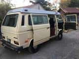 Classic beige VW Westfalia Vanagon pop-top camper van with open doors, ready for RV rental.