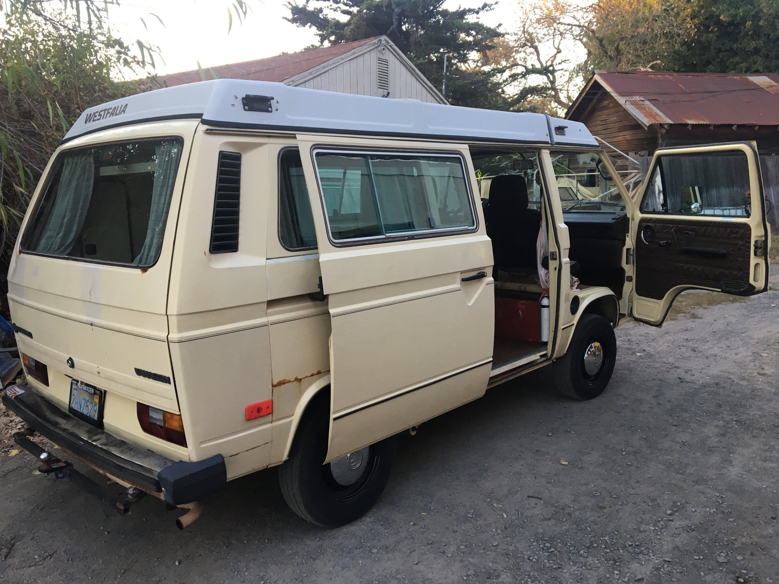 Classic beige VW Westfalia Vanagon pop-top camper van with open doors, ready for RV rental.