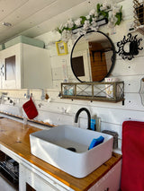 This RV rental kitchen features a white sink, wood counter, and charming decor with butterflies and flowers.