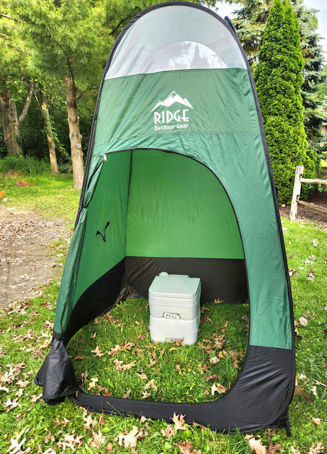 Green outdoor privacy tent with a portable toilet, perfect for camping and RV rental trips.