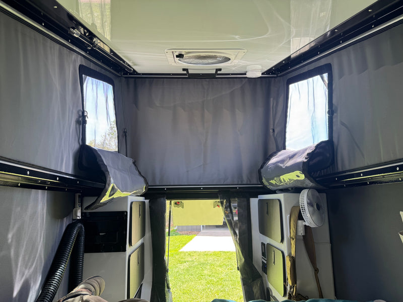 Interior of an rv rental pop-top camper, with ceiling fan, mesh windows, storage, and outdoor view. — photo 19