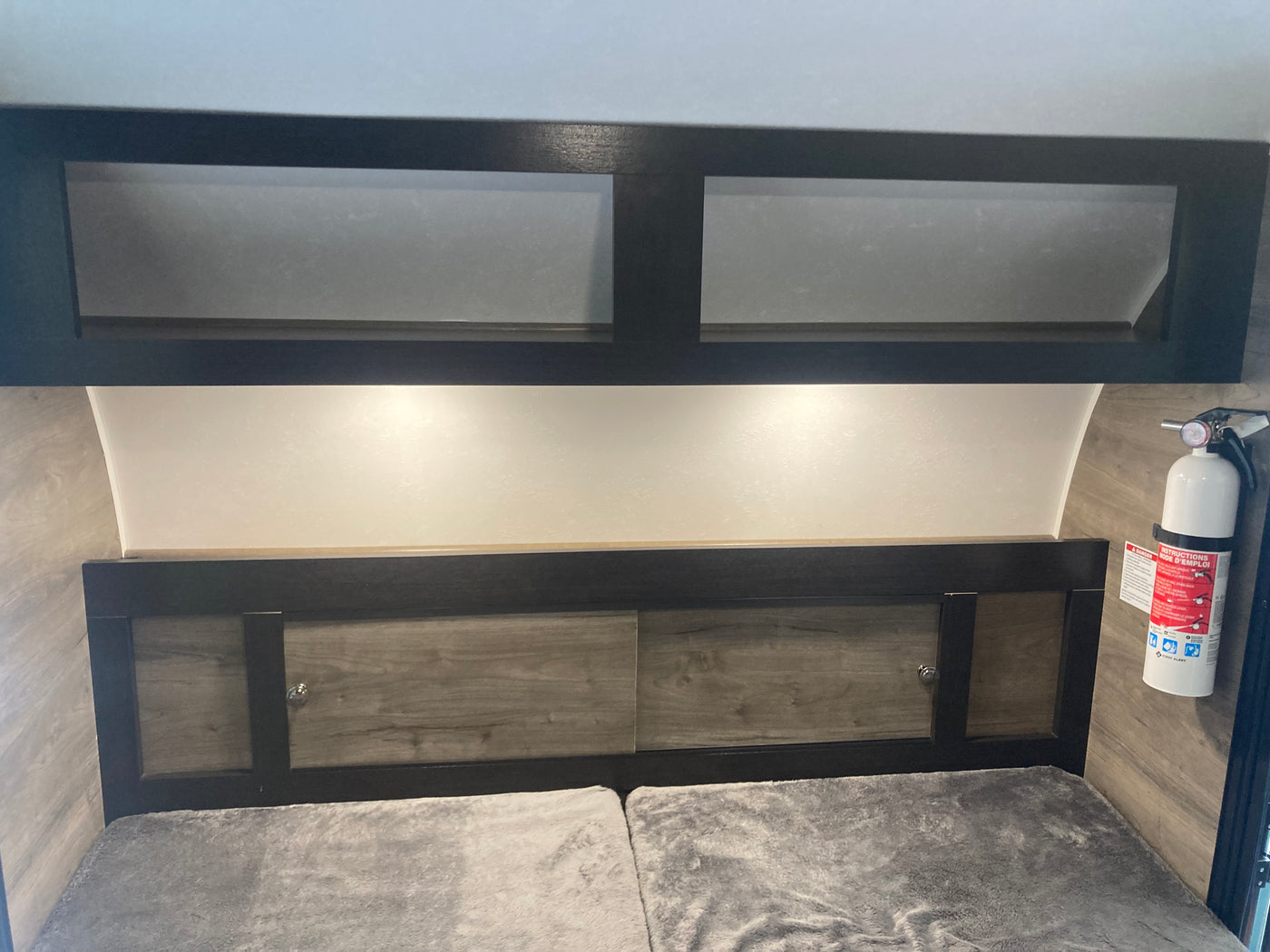 This RV rental features a comfortable bed, convenient overhead storage cabinets, and essential safety equipment like a fire extinguisher. — photo 6