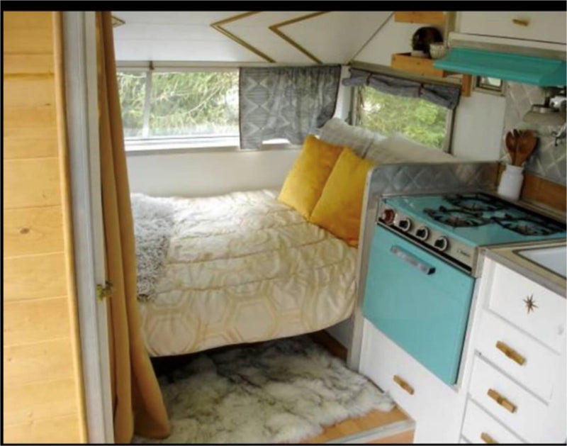  and plants.|Retro white & teal camper trailer (RV rental) with a cozy outdoor living area for glamping.|Cozy vintage RV rental interior with a comfy bed — photo 3