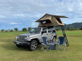 Silver Jeep Wrangler with TMBK rooftop tent, camping chairs, and cooler. Perfect RV rental for outdoor adventures.