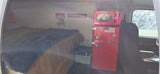 Cozy RV rental interior: bed, retro red fridge/microwave, power station, and mountain-themed decor for a comfy road trip.