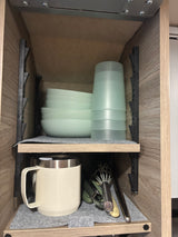 RV rental kitchen cabinet: neatly organized bowls, cups, and utensils on felt-lined shelves, perfect for compact living.