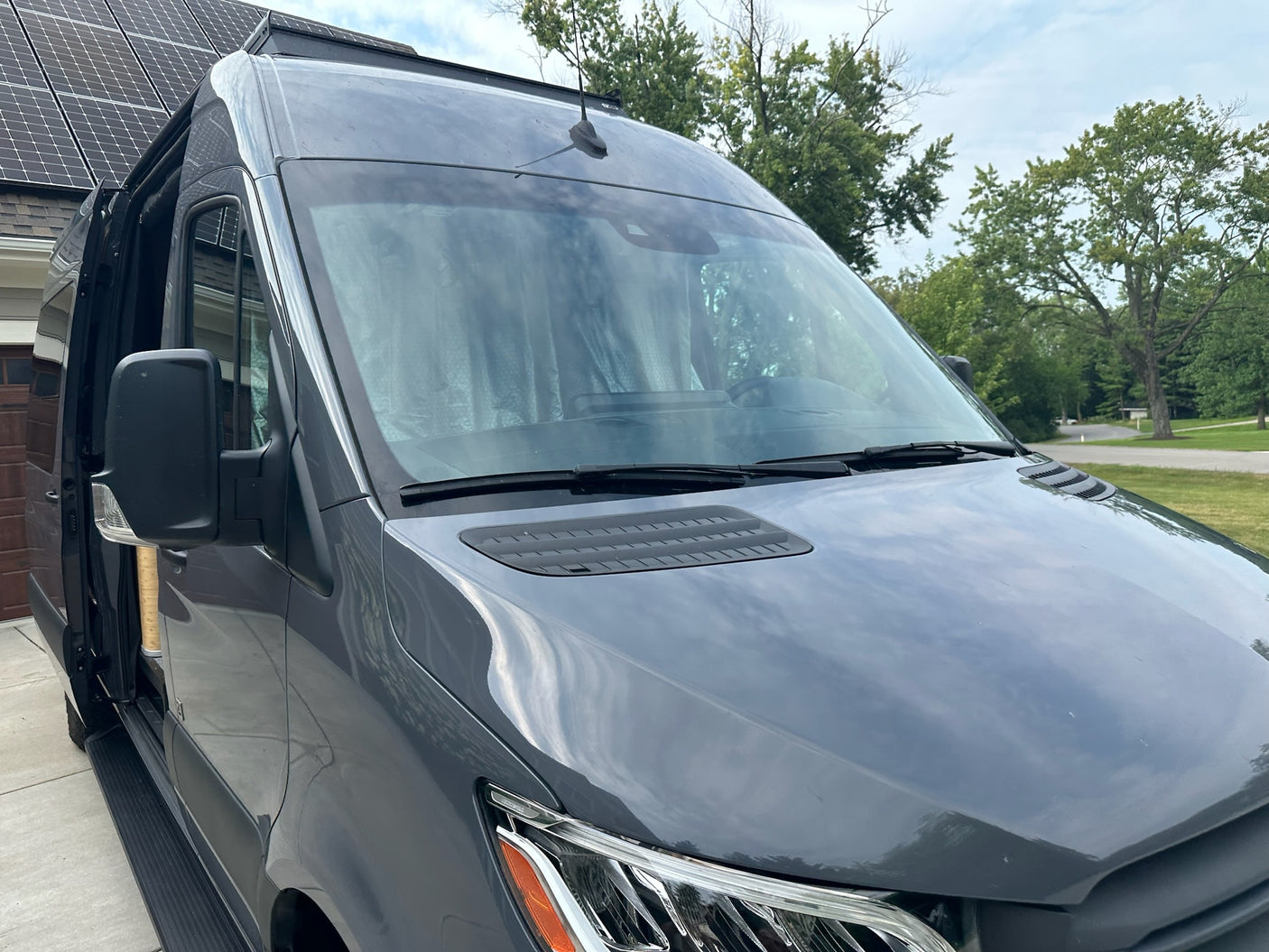 A modern gray Sprinter conversion van, ready for your RV rental. Features a visible antenna, hood vent, and running board.