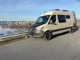 Adventure-ready Mercedes Sprinter camper van, ideal for RV rental, overlooks a scenic city and river.