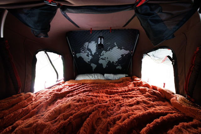  ready for adventures in nature with an SUV.|Comfortable sleeping area within an RV rental tent. Features a soft orange blanket