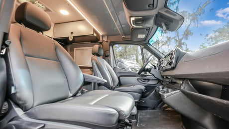 RV rental interior features comfortable grey seating, modern dashboard, and bright cabin lights for a relaxing journey.