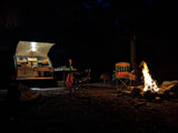  with a window overlooking a green field.|This RV rental offers a cozy camping experience: a comfy bed in a glowing teardrop trailer
